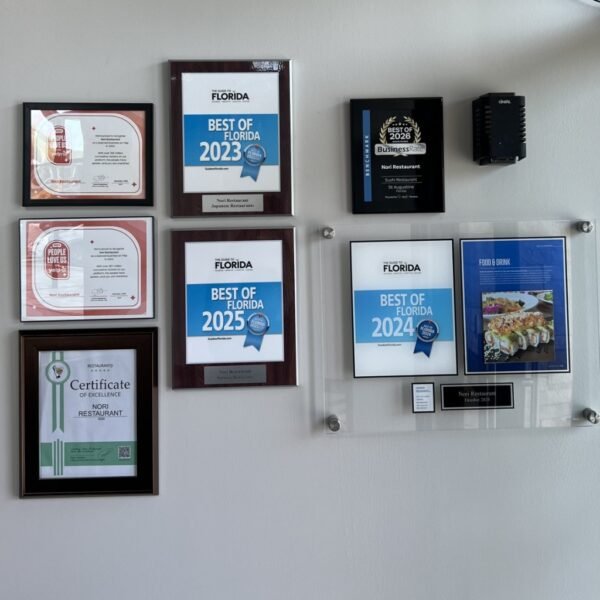 Nori Restaurant award plaques on display: Best of Florida 2023, 2024, 2025, BusinessRate Best of 2026, Yelp People Love Us awards, and Restaurantji Certificate of Excellence